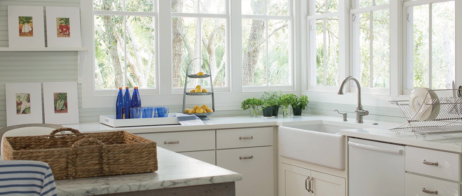 kitchen with big windows, white cabinetry and an island with wicker tray on top